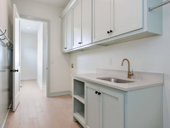Bright, clean kitchen featuring white cabinets, a gold faucet, and ample storage space at 6111 Passi.