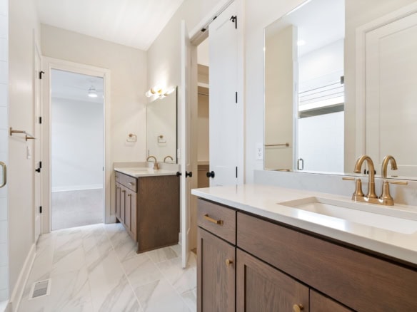 Bright bathroom featuring a double vanity with gold fixtures and a large mirror.