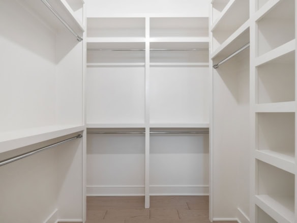 Spacious walk-in closet with multiple shelves and hanging rods for efficient storage.