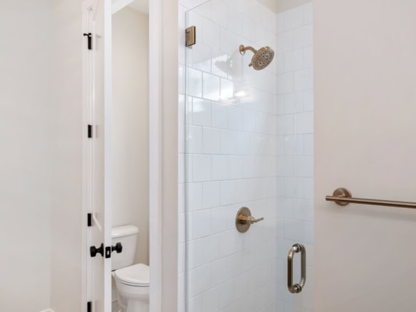 Bright, clean shower with white tiles and brushed nickel fixtures.