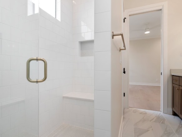 Elegant bathroom shower featuring white tiles and a glass door.