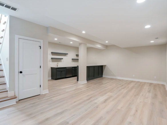 Bright, spacious basement with light wood flooring and built-in bar area.