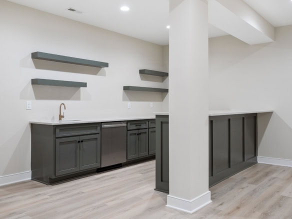 Modern kitchen with gray cabinets and floating shelves in a new home.