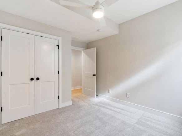 Bright, empty bedroom with white walls, closet doors, and ceiling fan at 6111 Passionflower Dr.