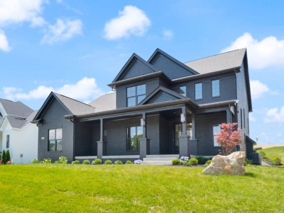 Black house with front porch and large windows in a suburban neighborhood.
