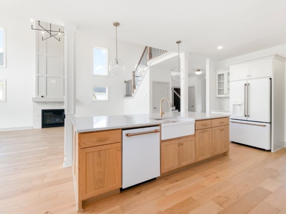 Bright, open-concept kitchen featuring white cabinetry and a central wooden island.