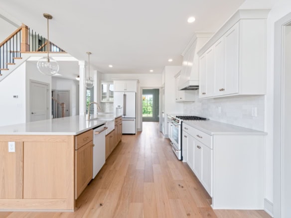 Bright, spacious kitchen featuring white cabinetry, wooden flooring, and modern appliances.