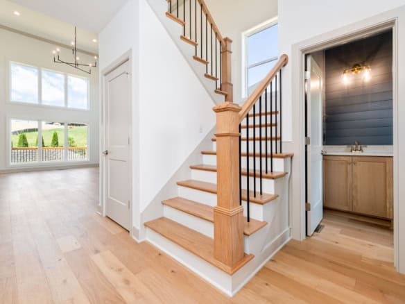 Elegant staircase with wooden steps and black metal balusters in a bright, open home.