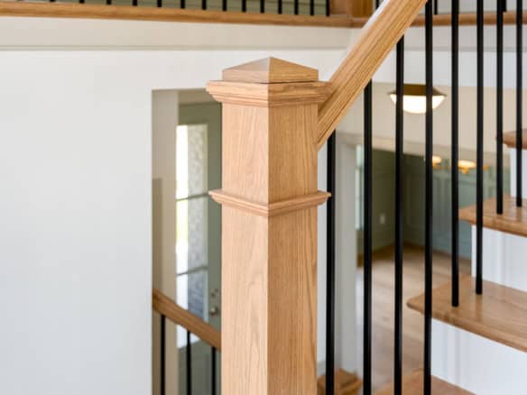 Wooden staircase handrail with black metal balusters at 6207 Brentwood Dr.