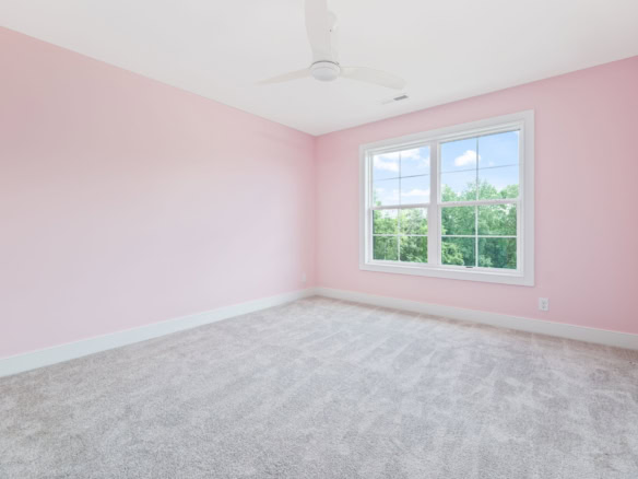 Bright, airy bedroom with pink walls and large window in 6207 Brentwood Dr.