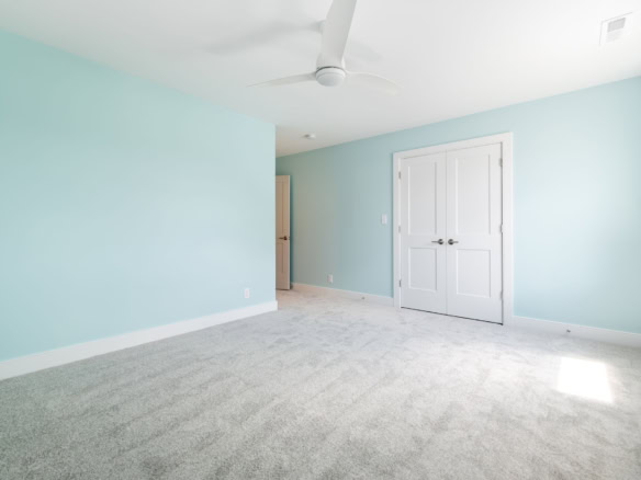 Bright, airy bedroom with light blue walls and plush carpet flooring.