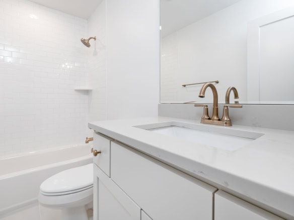 Modern bathroom with white tiles, bathtub, and sleek vanity.