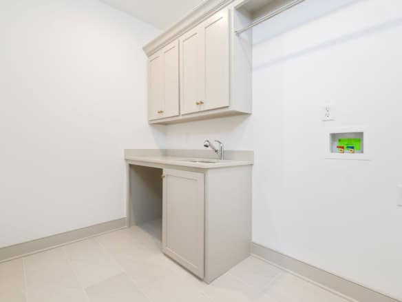 Bright laundry area featuring white cabinetry and a utility sink for convenience.