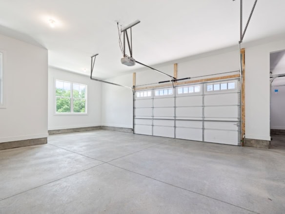 Spacious garage with new flooring, bright windows, and a clean, open layout.