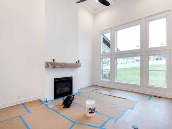 Spacious living room with fireplace and large windows in a new construction home.