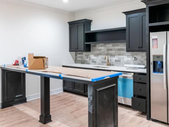 Newly renovated kitchen with black cabinets, gray backsplash, and stainless steel appliances.