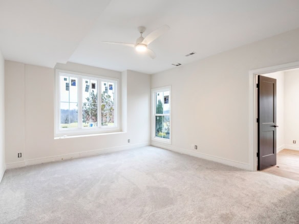 Bright living room with large windows, ceiling fan, and neutral decor.