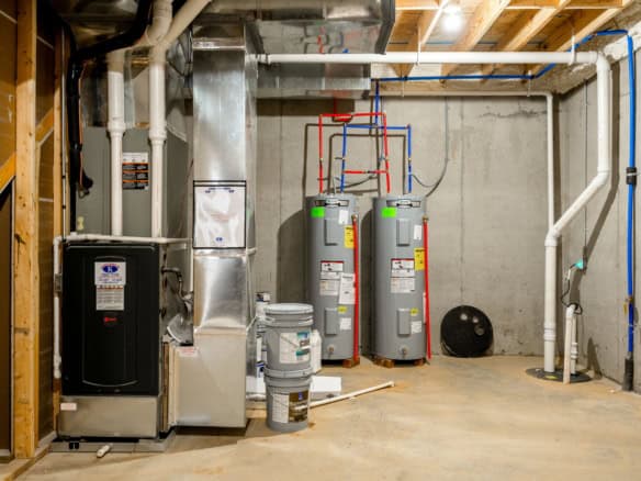 Image of HVAC system and water heaters in a basement utility room.