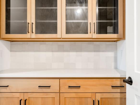 Kitchen cabinetry with glass-front upper cabinets and wooden lower cabinets.