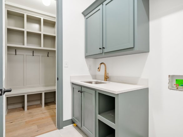 New laundry room with gray cabinets, white countertop, and built-in storage.