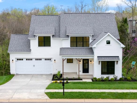 Beautiful white two-story house with gray roof, front porch, and landscaped yard.
