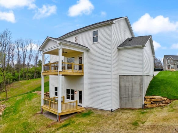 Modern white house with two-story decks on a sloped lot in a residential neighborhood.