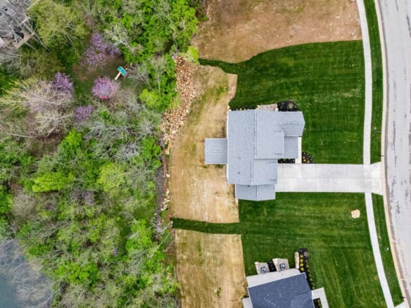 Aerial view of a house with landscaped yard and surrounding trees.