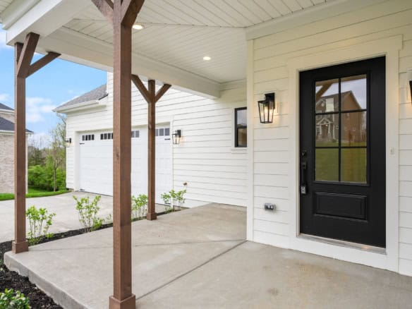 Modern front porch with black door and outdoor lighting.