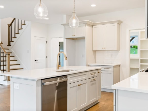Bright, modern kitchen featuring white cabinets, a central island, and pendant lighting.