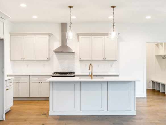 Bright, modern kitchen featuring white cabinets, island, and pendant lights.