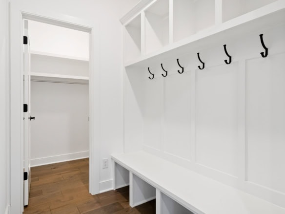 Bright white mudroom with hooks and built-in storage bench for organization.
