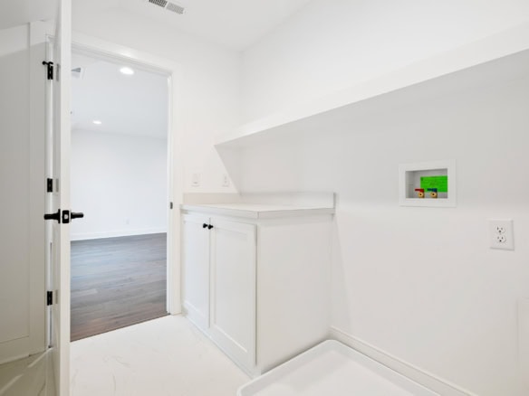Bright laundry room with white cabinets and wall niche.