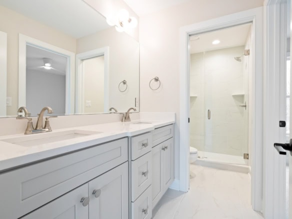 Bright bathroom featuring a double vanity, large mirror, and walk-in shower.