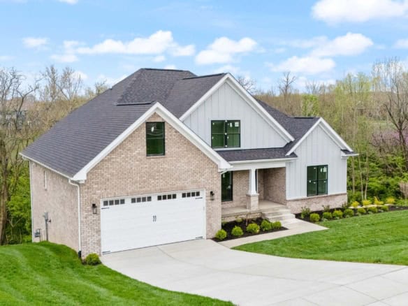 New custom-built house with brick and siding exterior, landscaped yard.