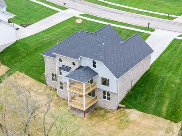 Aerial view of a newly built residential home with a gray roof and wooden balconies at 6505 Hypoint.