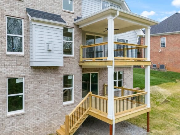 Custom wooden deck with stairs and railing at residential property.
