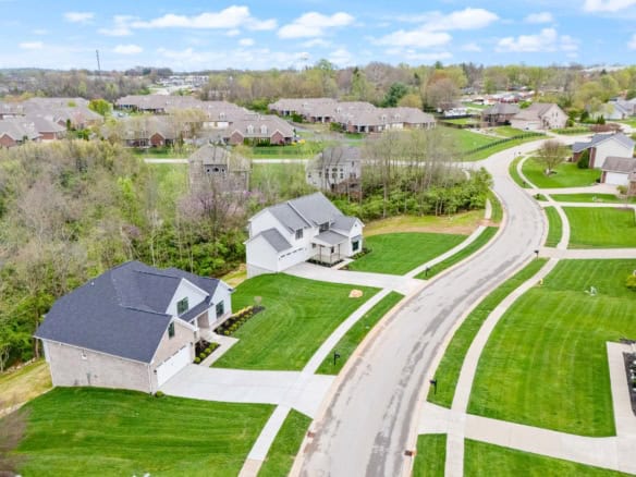 Aerial view of a residential area with new houses, green lawns, and curved roads.