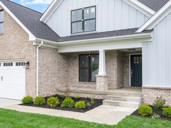 A house with brick and siding exterior, front porch, and landscaped yard.