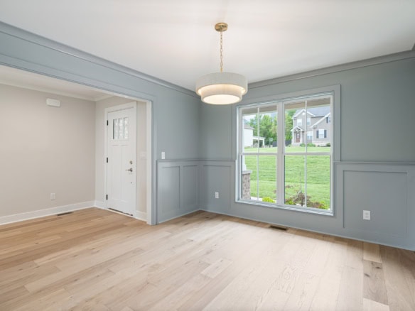 Interior of a bright, spacious living room with large windows and hardwood floors.