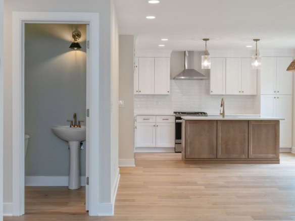 Modern kitchen with island and bathroom with sink in new home.