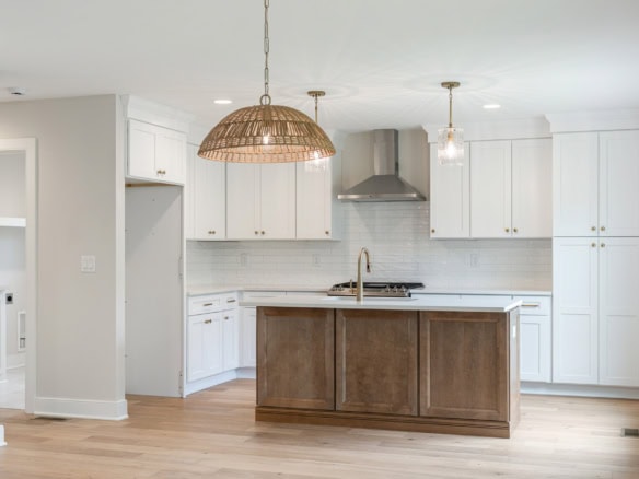Bright modern kitchen featuring white cabinets, a central island, and pendant lighting.