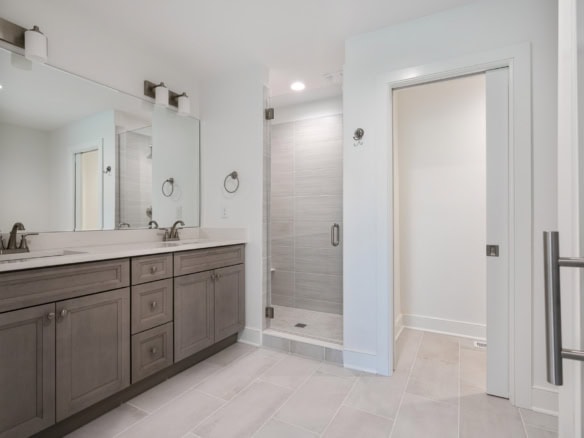 Bathroom vanity with double sinks and walk-in shower in modern home interior.