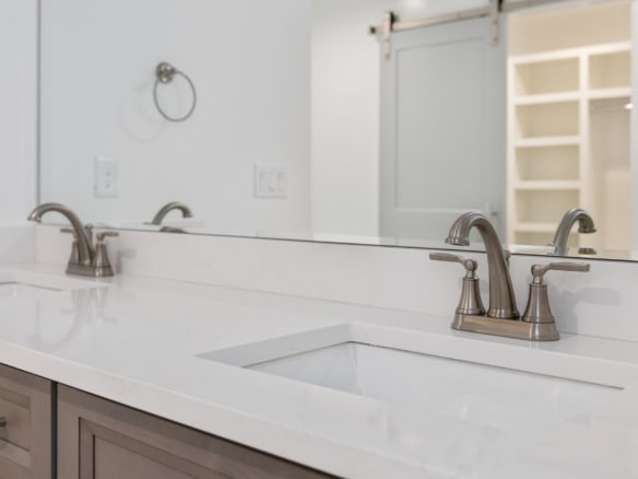 Bathroom vanity with dual sinks and sleek white countertop.