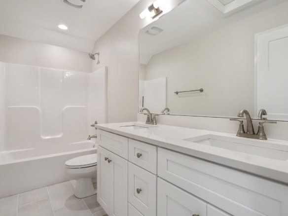 Bathroom with double sink, mirror, and white cabinetry.