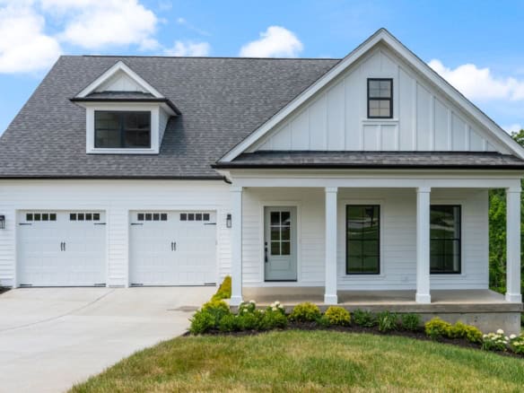 New white house with front porch, garage, and landscaped yard at 6603 Oakmont Cir.