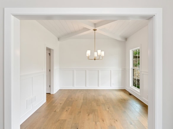Interior view of a bright, spacious room with white walls, large windows, and a chandelier.