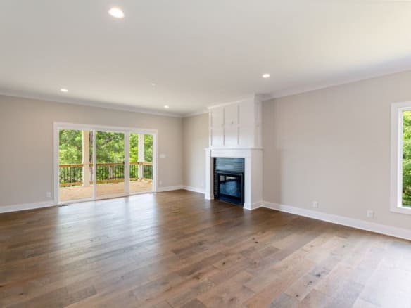 Spacious living room with hardwood floors, fireplace, and large windows.