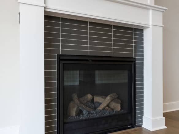 Fireplace with modern tile surround, built-in gas insert, and white mantel at 6603 Oakmont Cir.