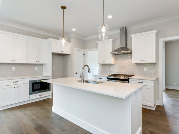 Modern white kitchen with island and stainless steel appliances.