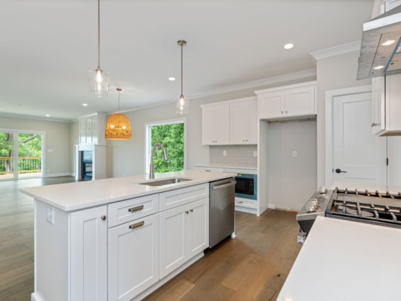 Bright, modern kitchen with white cabinets, island, and stainless steel appliances.